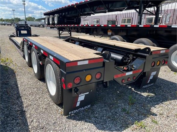 Fontaine 55 ton steel roller paver lowboy trailer with black finish, wooden deck, triple axle at rear, and rear mud flaps displaying Fontaine logo.