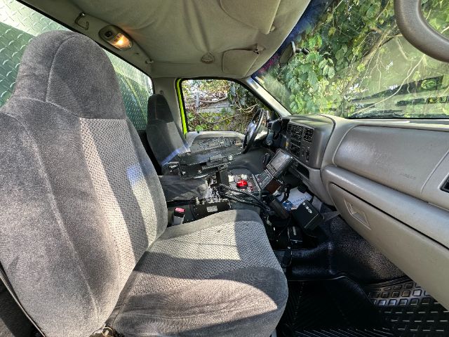Ford F-550 interior cab view showing front seats, dashboard, center console, and damaged center area with exposed wiring.