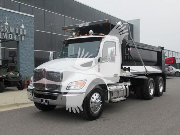 Kenworth T480 dump truck in white with black dump bed, front grille, chrome bumper, and dual rear wheels parked outside showroom.