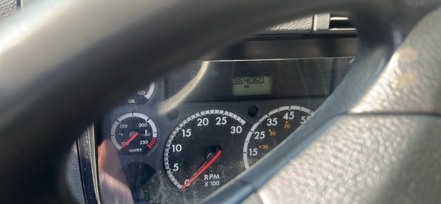 Dashboard of a Freightliner Cascadia truck showing tachometer and odometer with 364,606 miles display visible behind steering wheel.