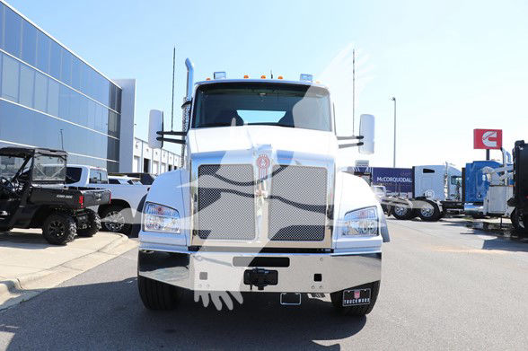 Kenworth T880 cab and chassis front view parked in dealership lot with other trucks in background.