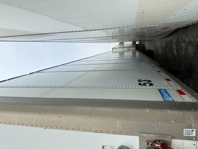 Tractor-trailer van side view showing white Stoughton dry van with the number 53 and reflective red/white markings.