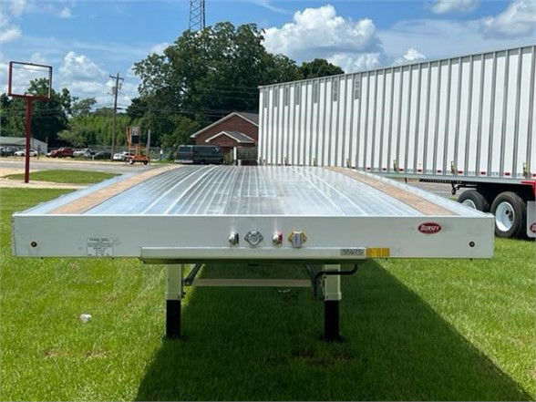 Flatbed trailer with aluminum deck showing Dorsey logo on front edge; front panel has control valves, lights, and labels.