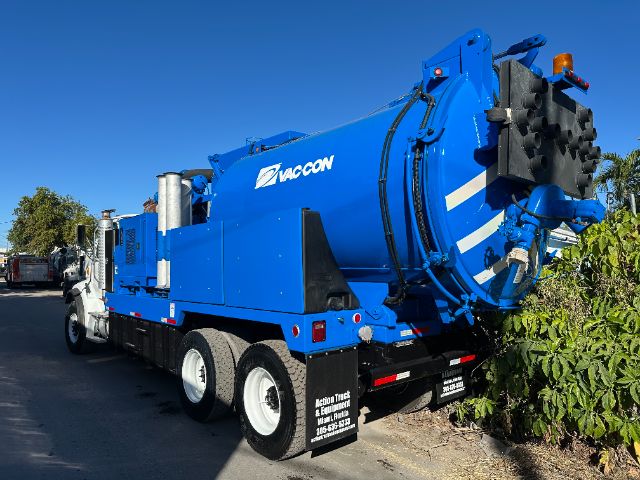 Vacuum truck rear and side view showing blue VACCON vacuum tank on a Sterling L7500 chassis, with rear spinner discharge, black mud flaps, and bumper; side text VACCON and model details not fully legible.