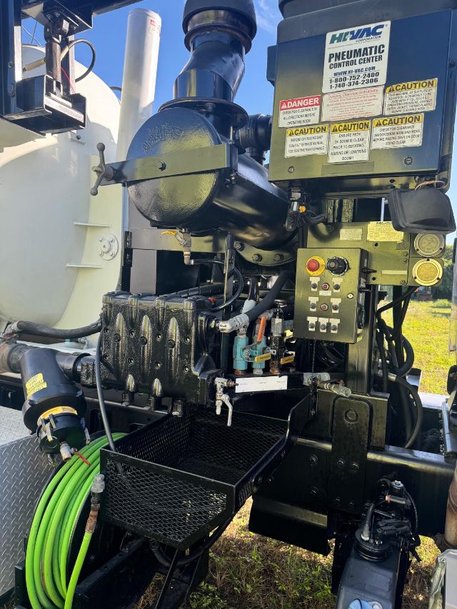 Freightliner 114SD engine bay with HiTEC Pneumatic Control Center label, warning stickers, control panel, hoses, and a green hose reel visible.