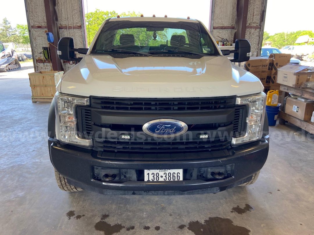 Ford F-450 front view showing headlights, grille, and bumper with Texas license plate. Emblem centered on grille, 'SUPER DUTY' lettering on hood, stock number visible in background.