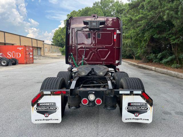 Rear view of a red Freightliner Cascadia tractor chassis with dual rear axles and mud flaps labeled Doggett Freightliner.