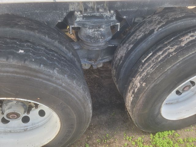Trailer axles with dual wheels, undercarriage showing landing gear and suspension, dirty tires with rims.