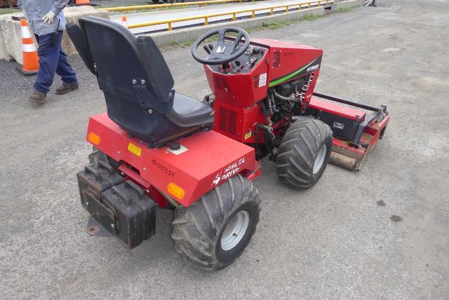 Red Steiner 415 utility tractor with a steering wheel, seat, and a mowing offset deck. Visible text on the body includes ' Steiner 415' and various labels near the rear and sides. Large off-road tires and a black seat.