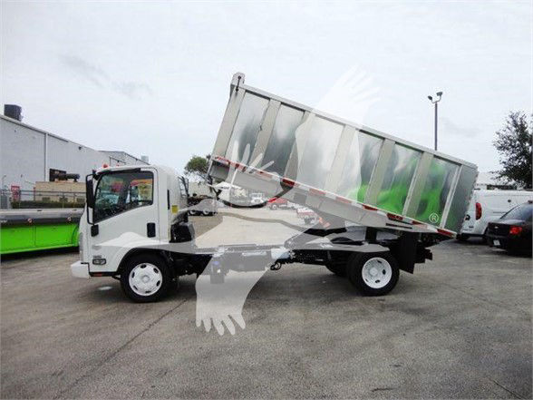 Isuzu NQR dump truck with tilting silver dump bed in lowered position, white cab, on dealership lot.