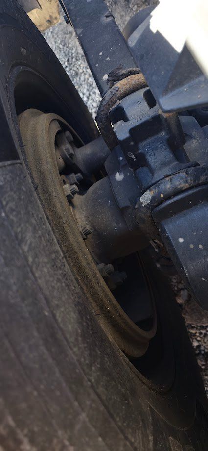 Kenworth T680 wheel hub and suspension components in close-up view showing the front axle and brake caliper.