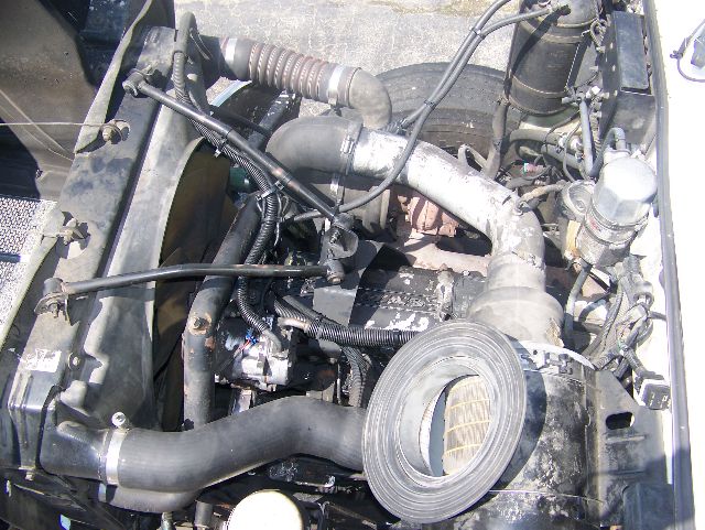 Peterbilt 335 engine bay showing air intake hose, turbo piping, hoses, and various engine components.