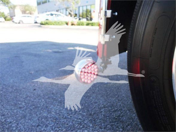 Tow truck rear wheel with a red-turred light and overlay graphic of a bird; the image shows a large tire and a red round marker near the wheel.