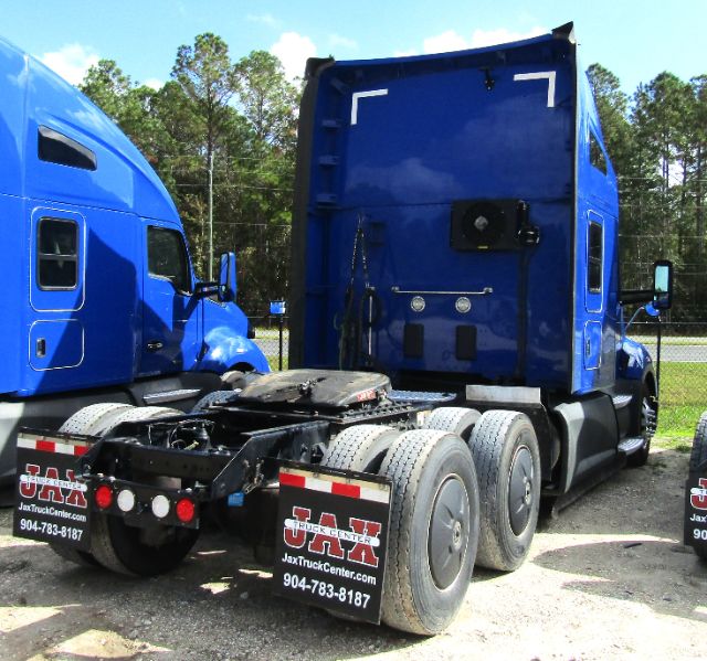 Truck rear view of a blue 2020 Kenworth T680 cab and chassis, showing the rear axle setup and mud flaps with Jax Truck Center logos and phone number.