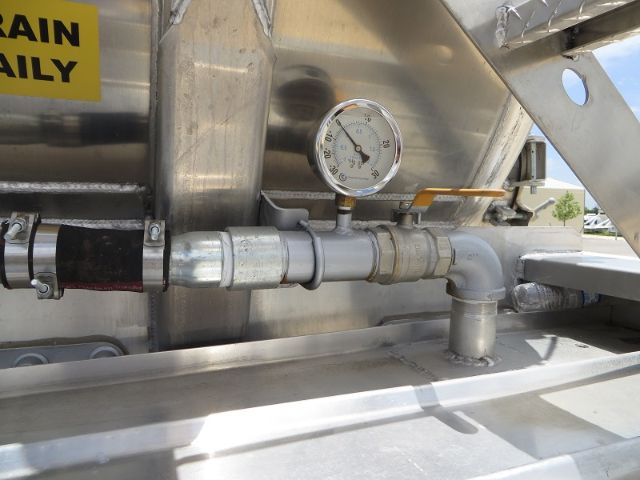 Vacuum tank trailer with gauge mount and stainless piping showing a pressure gauge and elbow fittings.