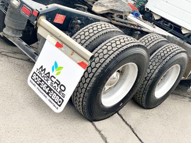 Volvo VNL 670 wheel area showing dual rear axles and tire treads with a sign reading Macro Trucksales