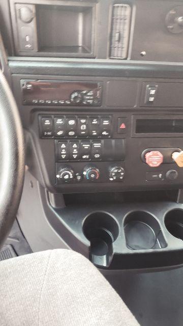 Interior of a 2019 International conventional sleeper truck showing dashboard controls, radio, climate dials, and cup holders.