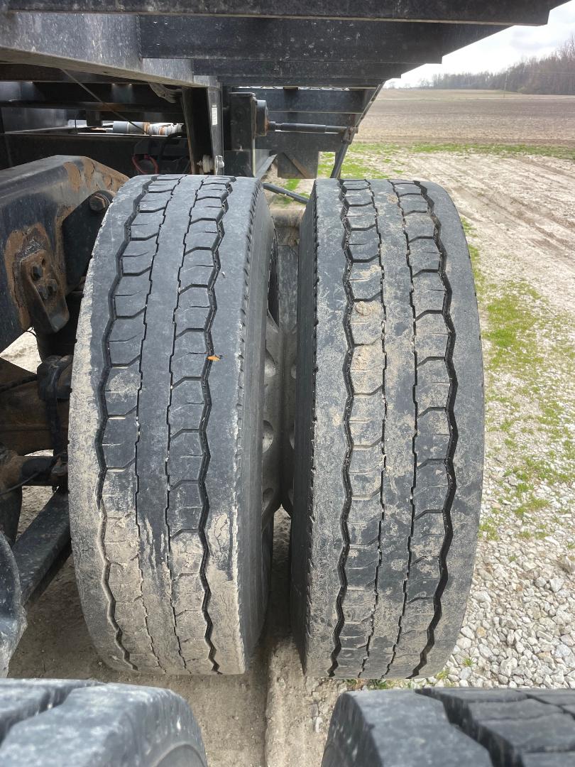 Truck tandem axles with worn dual tires showing tread wear and dirt buildup.