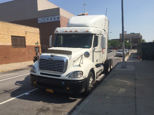 2009 Freightliner Columbia conventional sleeper truck in a city street setting, white cab with a high sleeper, grille front view, parked curbside.