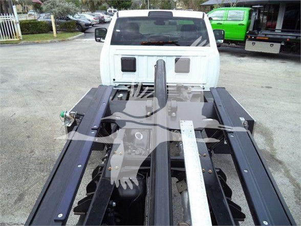 Ram 5500 Tow truck chassis with bed frame and rear hitch seen from behind a white truck cab.