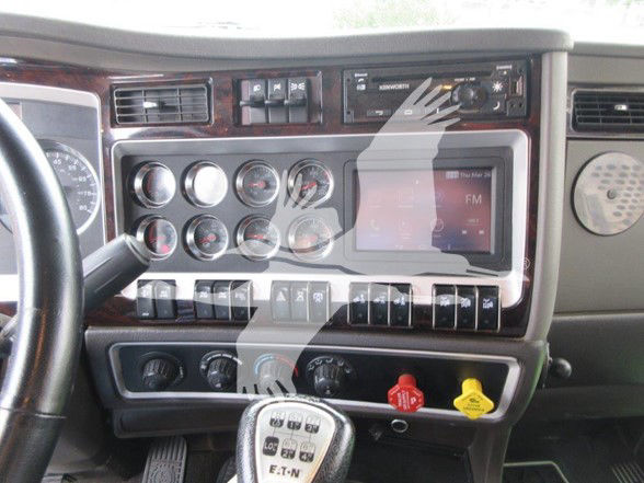 Kenworth W900L dash and steering wheel showing instrument cluster, radio, and controls.