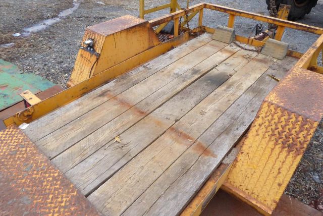 Trailer bed showing wooden planks and yellow metal frame with diamond plate edges.
