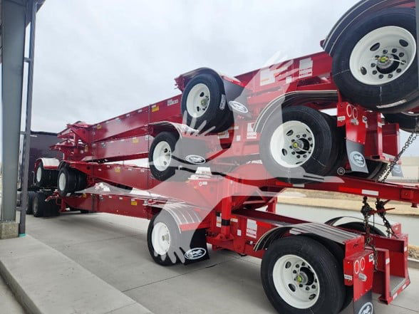 Container trailer stack in red showing multiple axles and white wheels.
