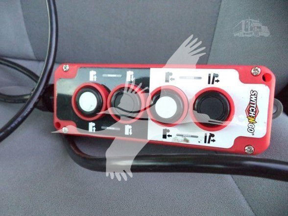 Isuzu NRR interior showing a red and white switches panel with four circular knobs and a black switch, labeled with icons and arrows.