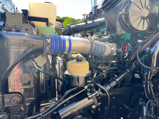 Peterbilt truck engine bay showing coolant reservoir, blue silicone hoses, and various engine components.
