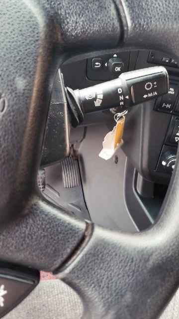 Truck interior view showing column shifter with D N R positions and ignition area; key tag hanging near steering column.