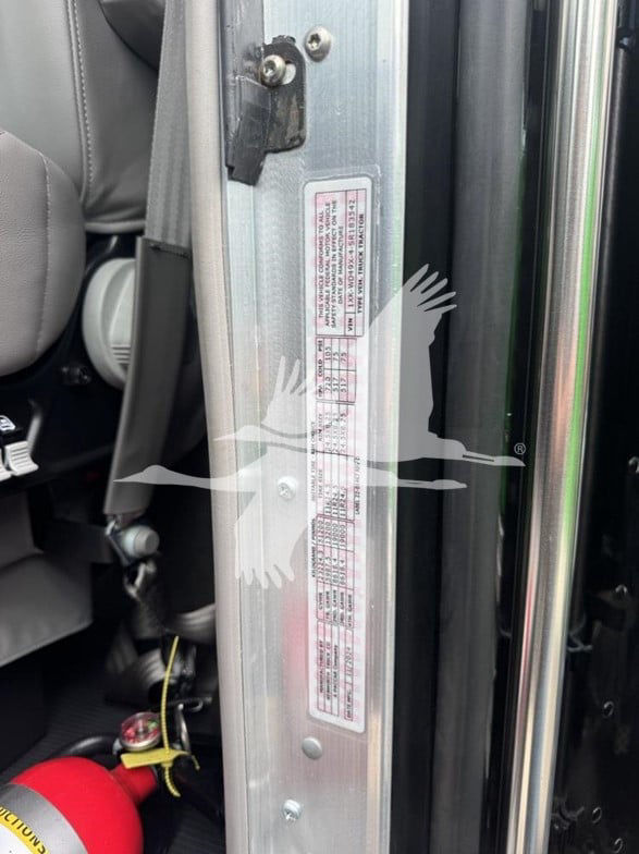 Kenworth W900L truck interior door jamb label with VIN and specifications visible on metal pillar.