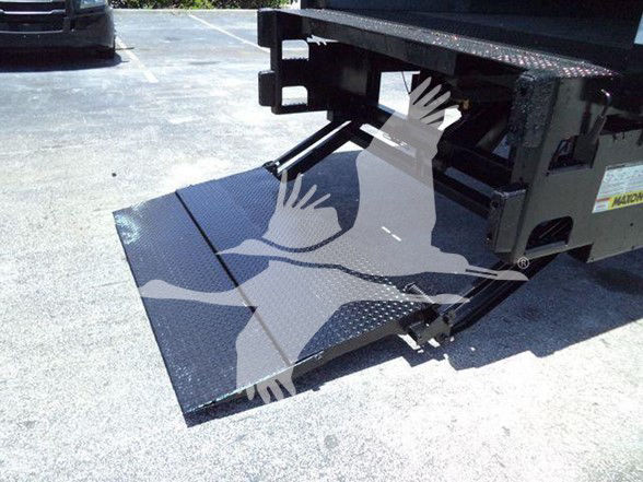 Truck with a lowered silver aluminum loading ramp extended behind the cab area; visible black metal frame and platform with textured surface.