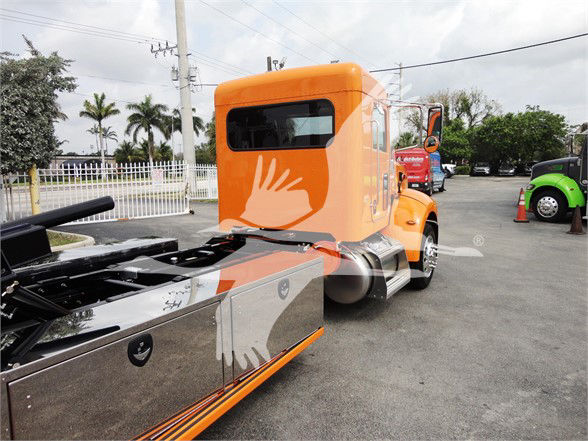 Peterbilt 337 cab connected to a chrome-finished flatbed trailer in orange livery.