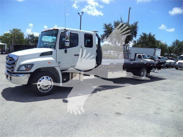 White 2025 Hino L6 tow truck with dual rear wheels and flatbed, side view showing cab and flatbed bed.