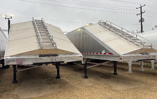 Aluminum hopper trailers on supports with ladders and safety rails, new condition, reflective striping along side.