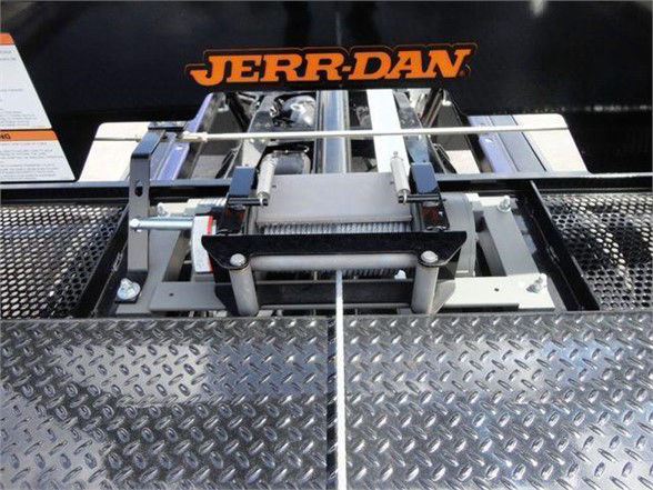 Tow truck platform showing a hydraulic winch assembly mounted on diamond plate steel, with JERR-DAN branding visible above.