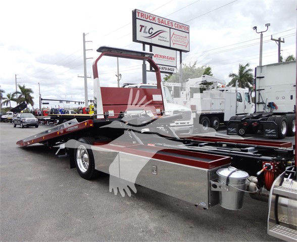 2022 Peterbilt 337 tow truck chassis with flatbed, red and silver color, front deck, hydraulic winch, and auxiliary tanks visible.