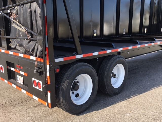 Great Dane trailer rear wheel area showing dual rear axles with white rims and black tires, side railing, and reflectors.