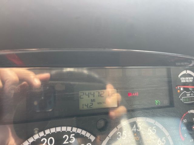 Digital odometer and gauge cluster readout inside a Freightliner M2 showing 244,472 miles and 11.2 volts, plus a brake warning and other indicators.