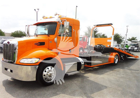 2022 Peterbilt 337 tow truck in orange with flatbed, front chrome bumper, large side mirrors, and extended cab.