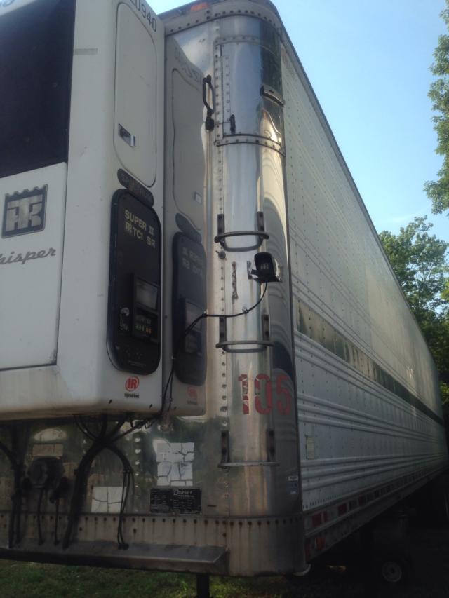 Trailer side showing reefer unit with Dorsey branding and stainless vertical support post. Visible are two digital meters, control panels, ladder rungs on the post, and riveted aluminum trailer skin.