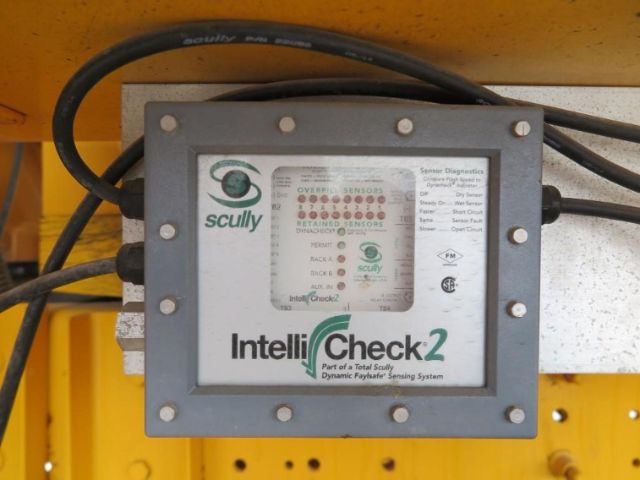 IntelliCheck-2 diagnostic module by Scully mounted on yellow machinery. text reads IntelliCheck-2 with Scully logo and diagnostic indicators.