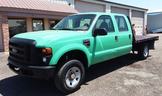 Ford F-250 4x4 crew cab flatbed pickup showing mint green exterior and black front grille, with flatbed at rear.