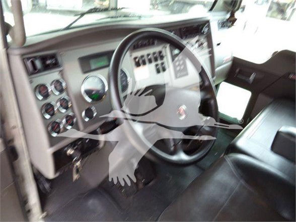 Truck cab interior showing steering wheel and dashboard of a Kenworth T370 with gauge cluster and control switches.