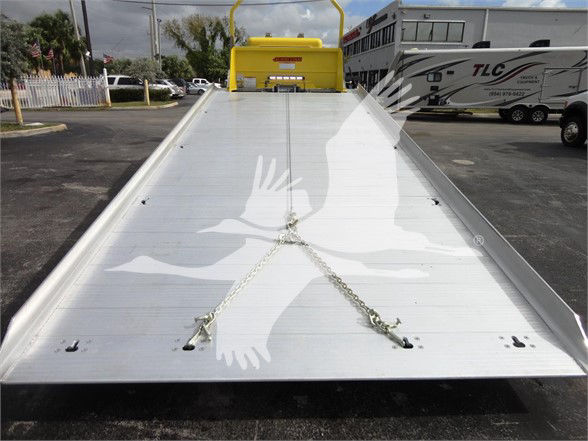 Flatbed tow truck bed with chains and yellow cab back, Peterbilt 337 design visible in background.