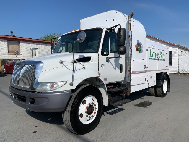 2006 International 4300 garbage truck with white cab and front chrome grille, Love Box branding on the side, side exhaust, and a large refuse body.