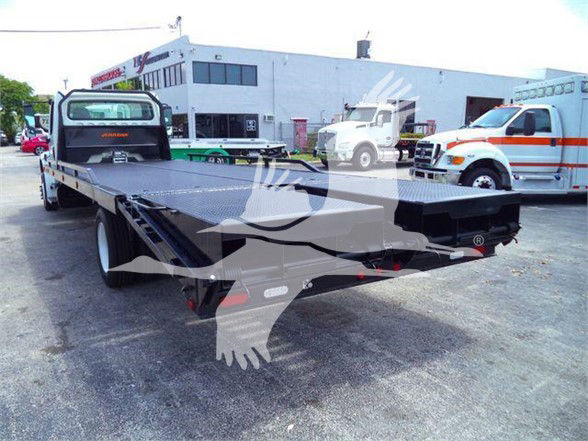 Flatbed truck deck with Freightliner Business Class M2 106 style rear view showing long wheelbase, black steel flatbed, and surrounding service area.