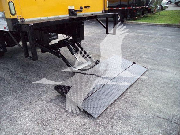 Truck lift/ramps attached to a yellow International DURASTAR 4300 with diamond plate folding ramp deployment.