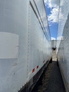 Two long light-gray Great Dane dry van trailers seen from the side, with riveted panels and red reflective markers along the lower edge.