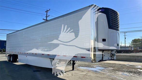 Trailer side view of a Vanguard Cool Globe refrigerated trailer with a white exterior and a refrigeration unit at the front.